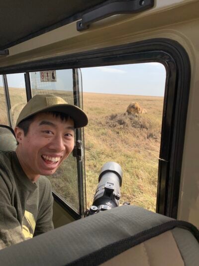 Michael C. with huge cameras sticking outside of safari jeep. Very excited to be so close to a lion.