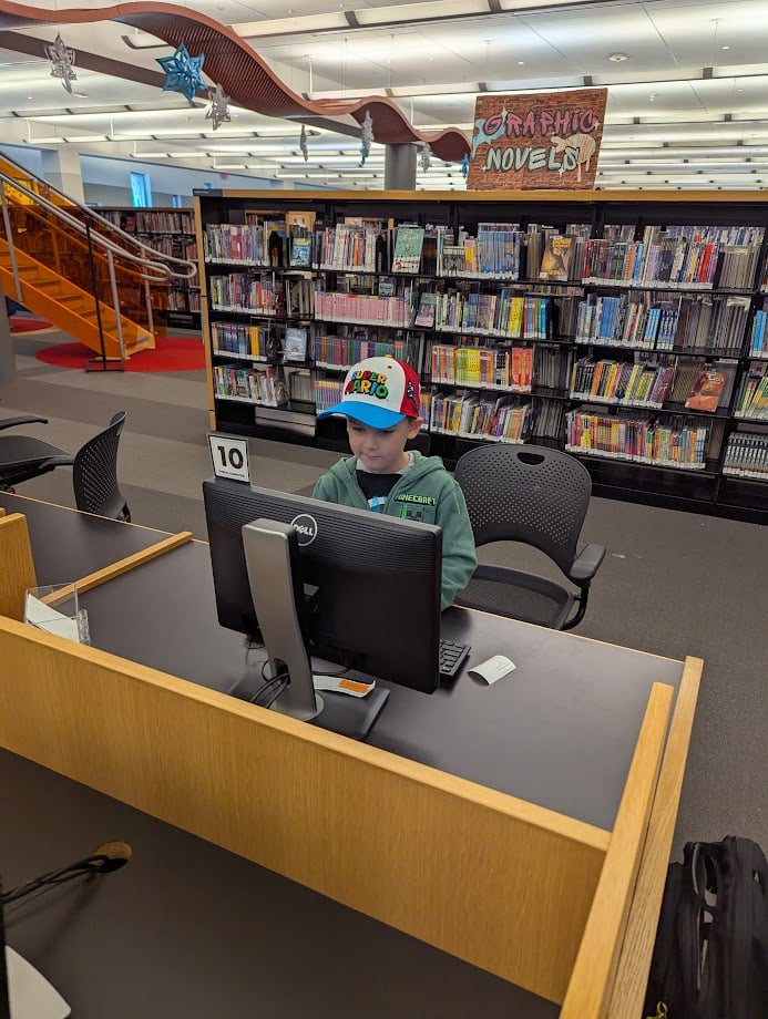 Child playing on a computer in a library