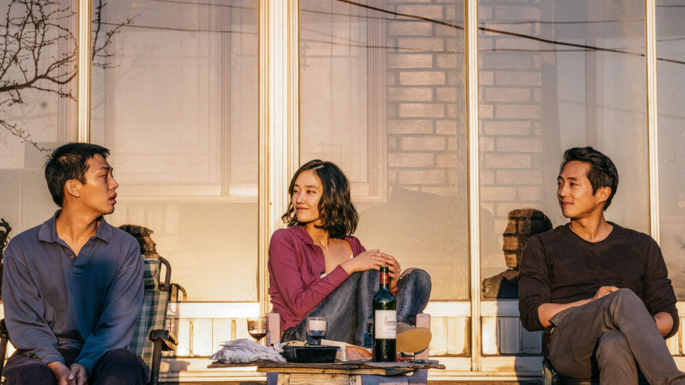 The three main characters in the film "Burning", sitting side by side on a porch.