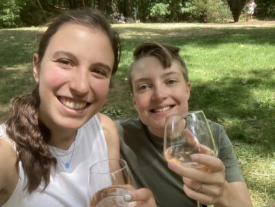 two people sitting on grass toasting with champagne