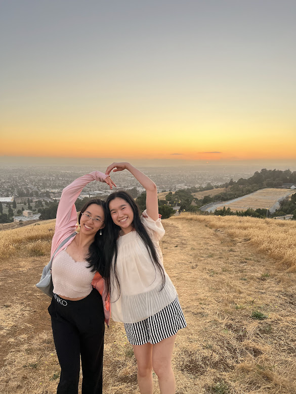 two people making a heart against the sunset