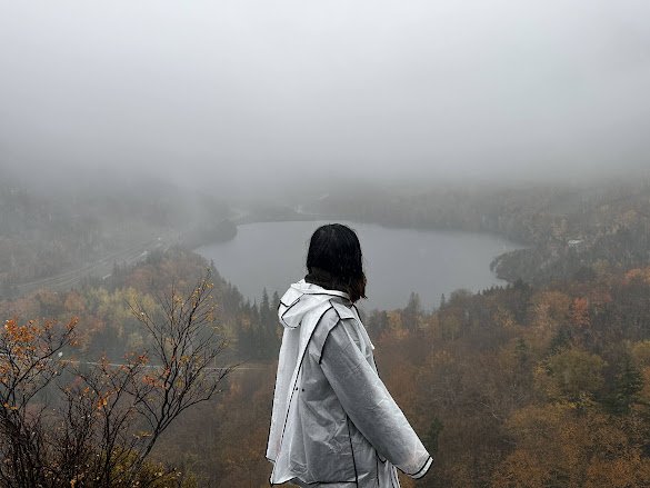 person soaked in rain looking at a lake in the background