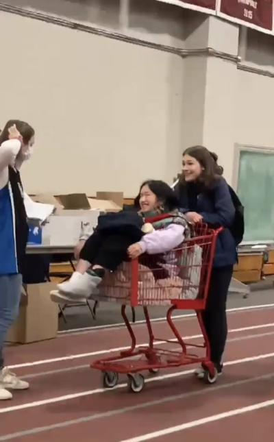 person sitting in shopping cart with someone else carting them. third person looks very confused