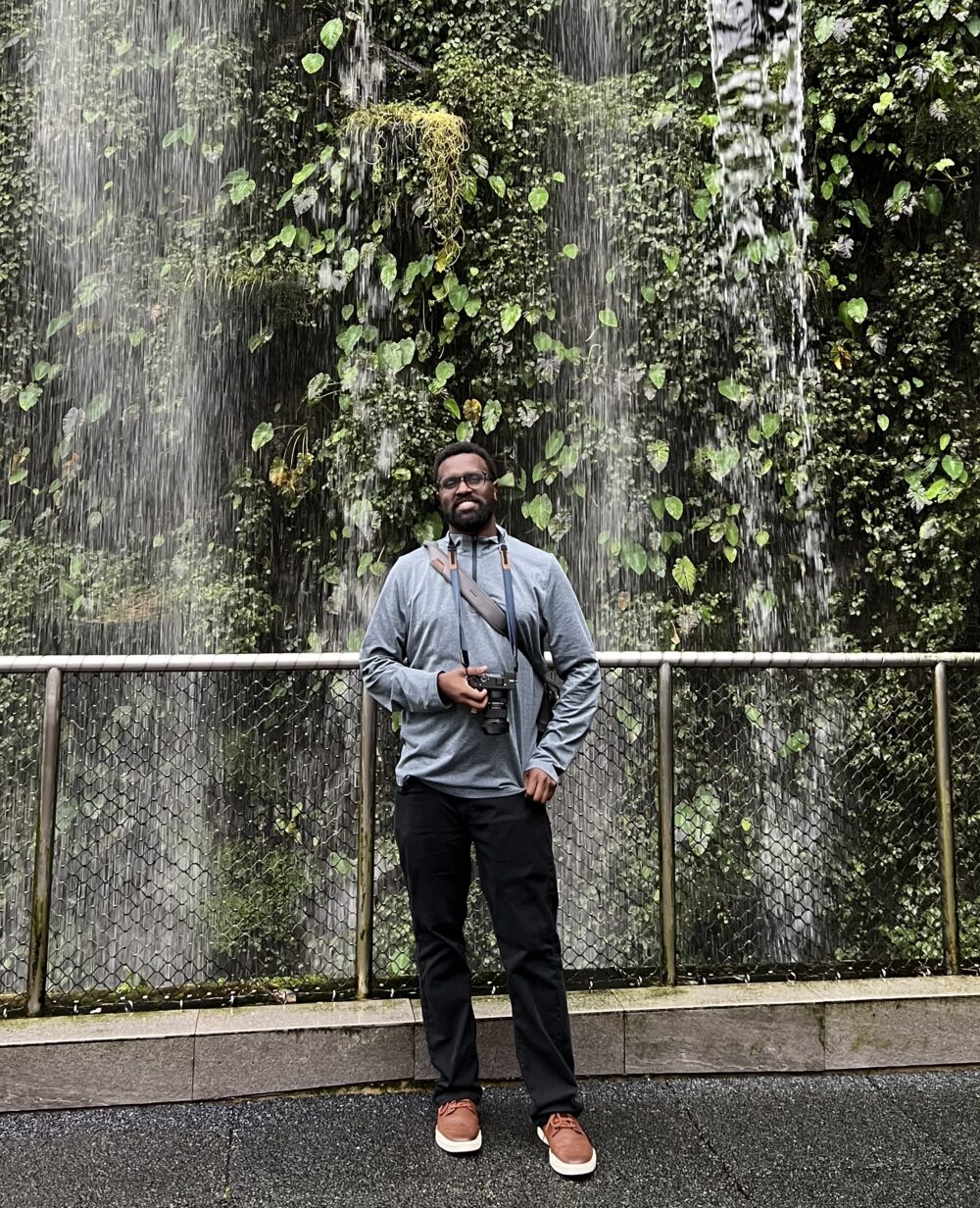 Man standing in front of greenery and waterfall