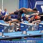 Swimmers dive off starting blocks