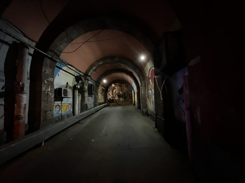 Graffiti Tunnel at Night – A dark, narrow tunnel with stone arches and scattered streetlights is covered in graffiti and urban artwork, giving it an atmospheric and moody feel.