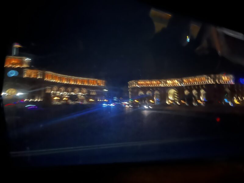 Blurred Nighttime Cityscape – A moving shot captures a grand, illuminated building in Yerevan at night, with glowing arches and a blurred effect adding a sense of motion.