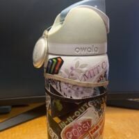 A white Owala water bottle wrapped in stickers