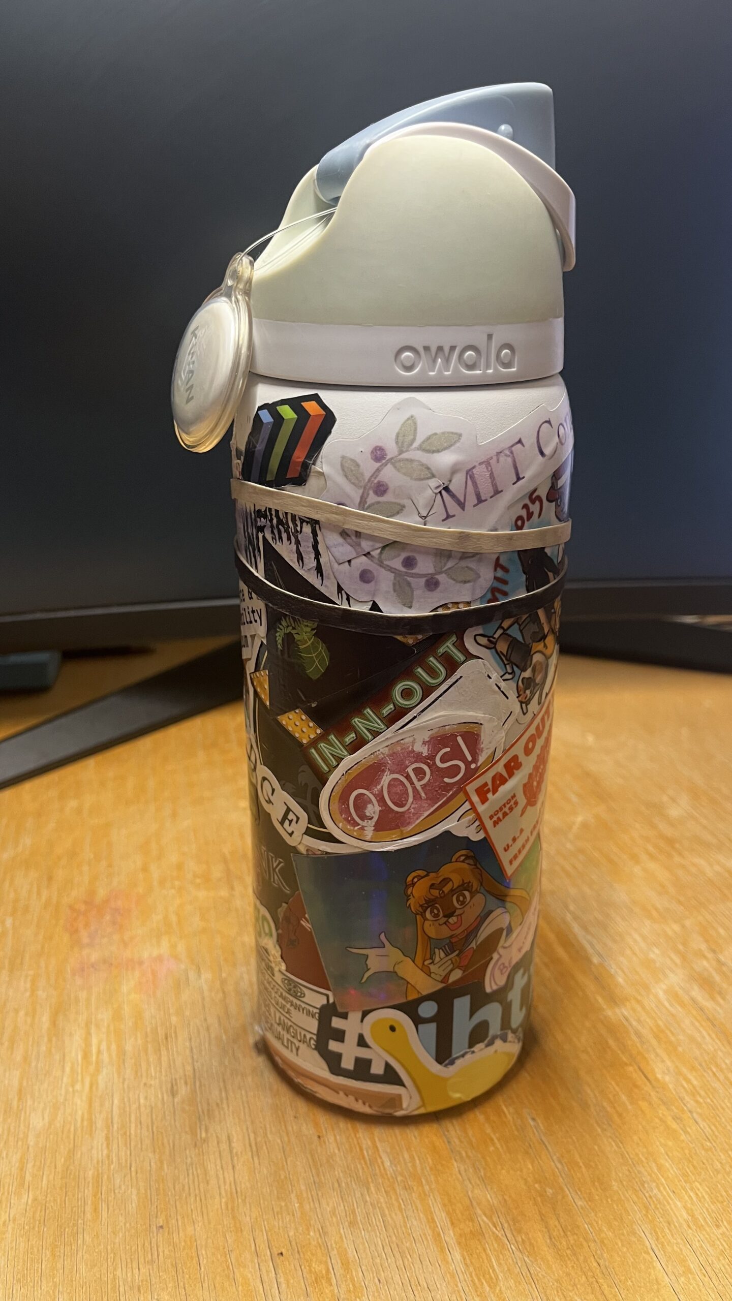 A white Owala water bottle wrapped in stickers