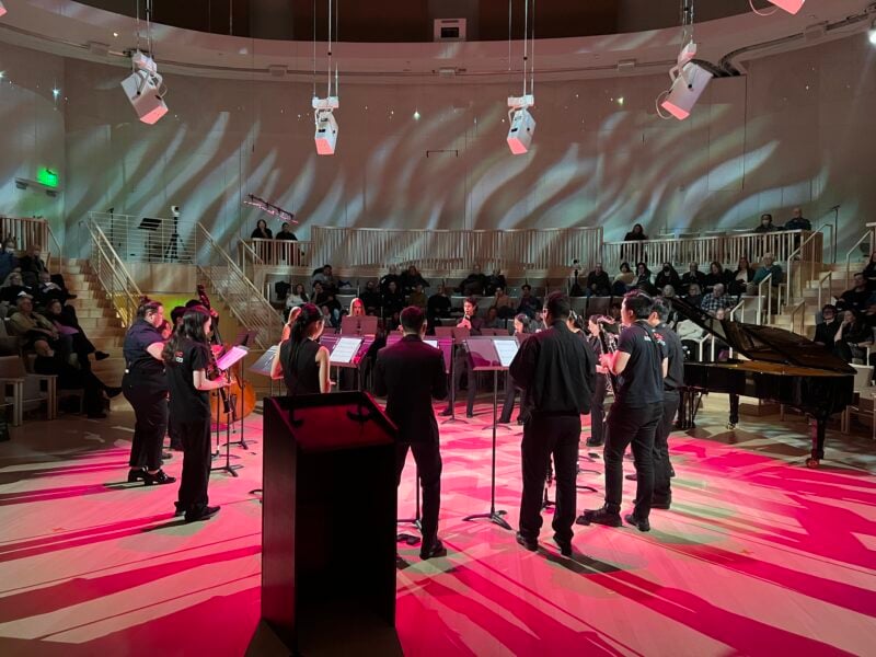 A group of clarinet players perform in a circle.