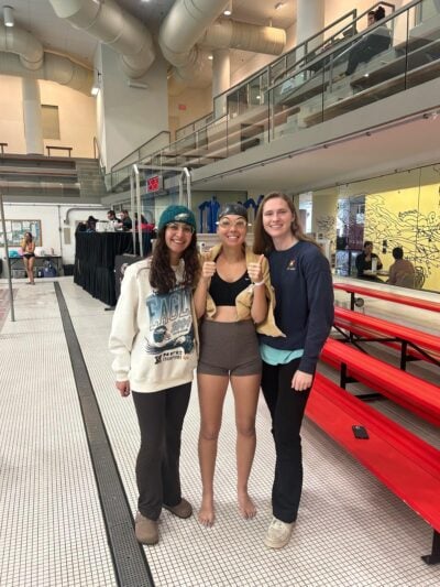 Three people smiling next to a pool.