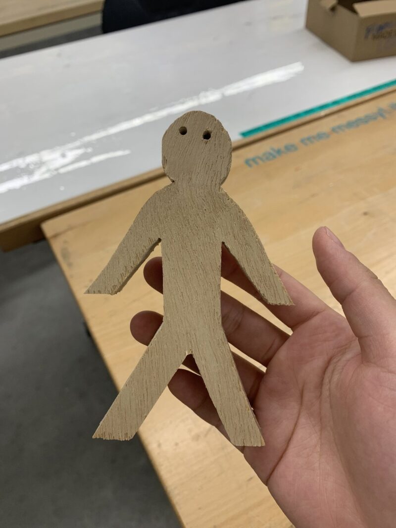 A person presents a wooden figure on a table, emphasizing the intricate design and natural beauty of the material.