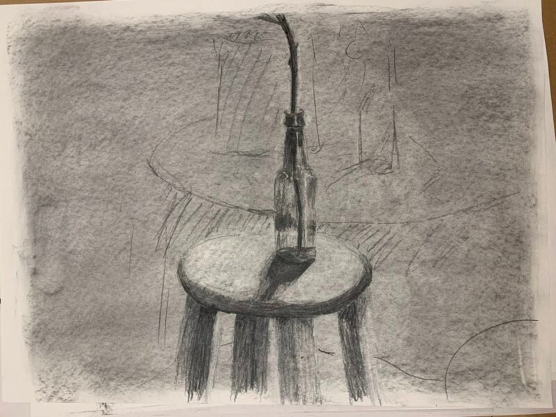 The sketch uses a combination of soft and hard pencil techniques to create depth. The glass bottle is centrally placed with a narrow neck, and the black hose spirals from the bottle's top, curving slightly downward. The round table, depicted with shading to suggest a light wood texture, contrasts the heavily shaded background, which consists of varying shades of gray and rough lines that suggest additional objects in the scene. Overall, the composition emphasizes the relationship between the bottle and the table while creating a muted, atmospheric effect.