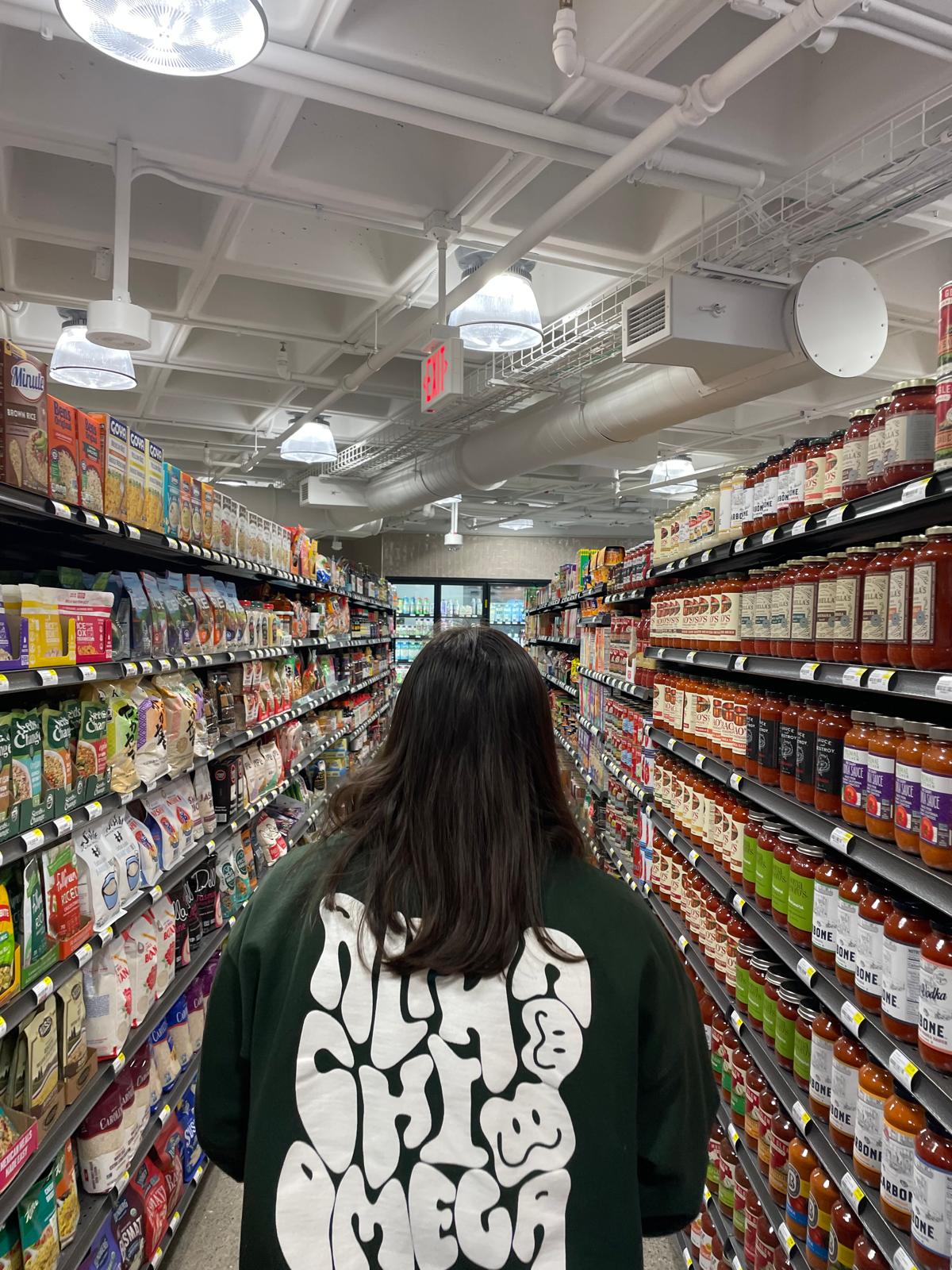 Girl walking down an aisle of a gorcery store.
