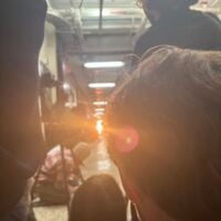 Obscured viewpoint of people in a hallway. Bright light with lens flare is the focal…