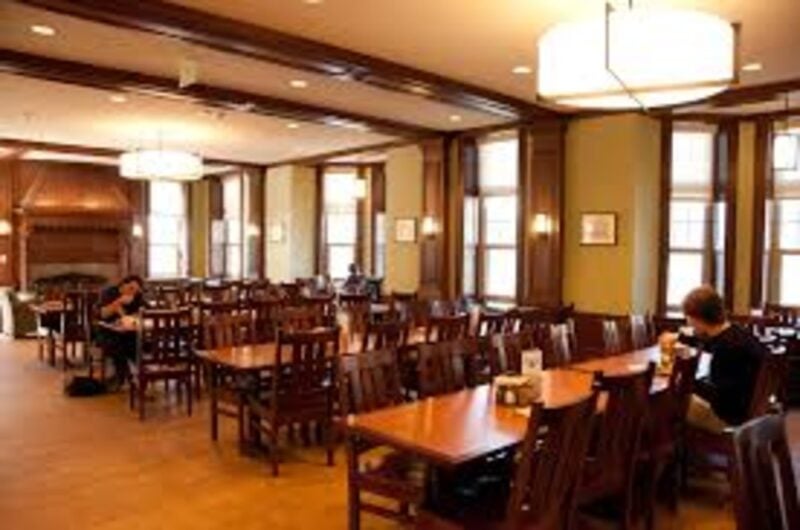 A dining area with wood floors, tables, and chairs, and warm lighting.
