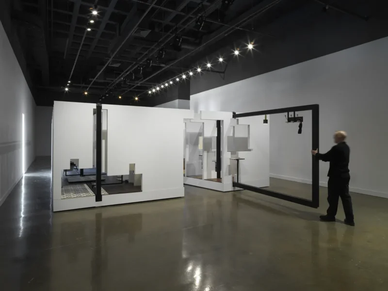 a photo of a large room with a white structure in the middle and someone pushing a black frame