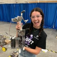 Girl holding aluminum robot with multiple arms.