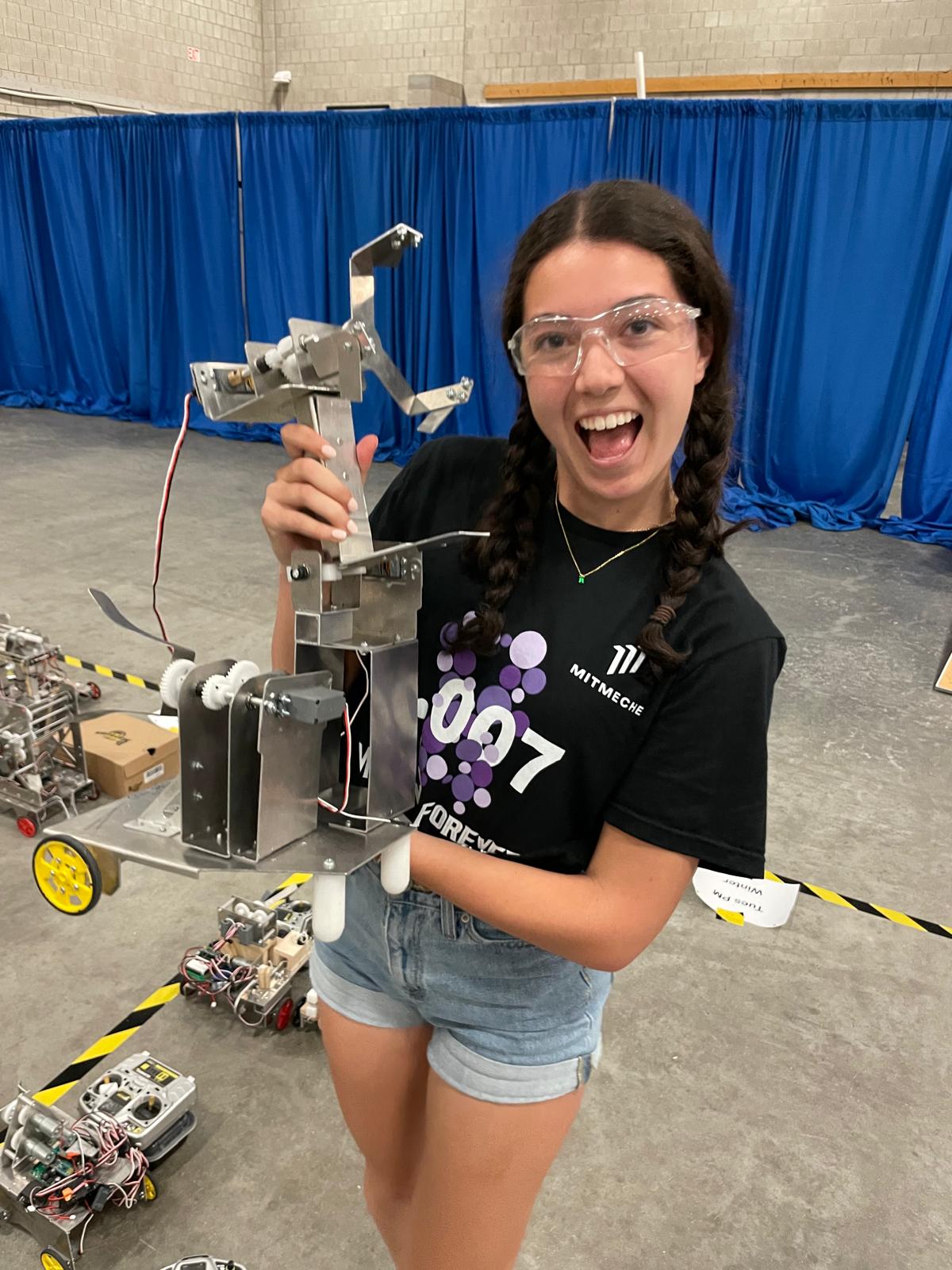 Girl holding aluminum robot with multiple arms.