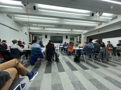 a picture of a room with many people sitting in it facing towards the front