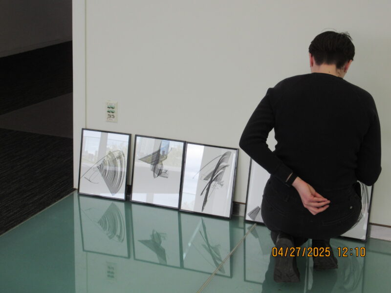 a person kneeling next to a wall with several prints
