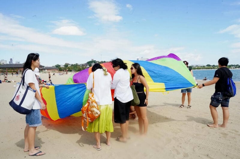 people on the beach setting down a rainbow parachute