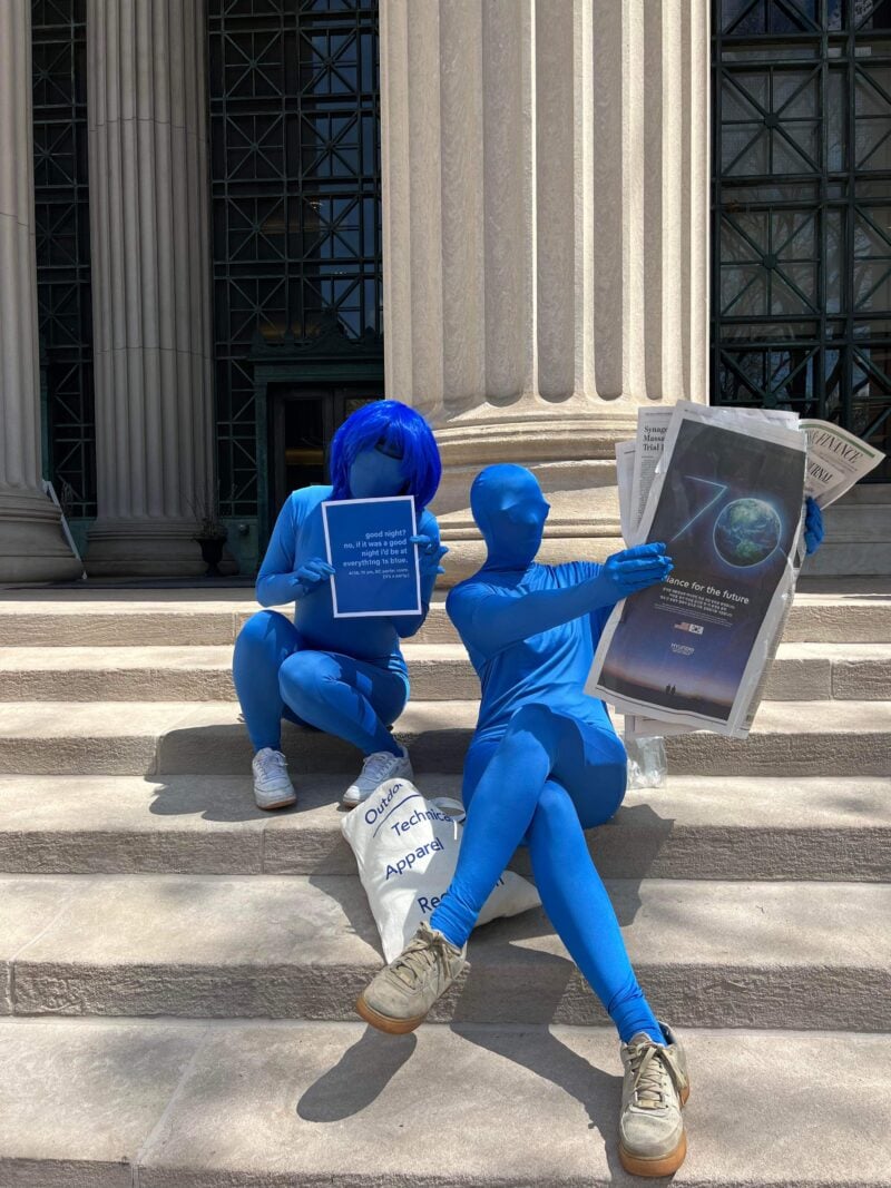 people in blue morph suits sitting on the steps of lobby seven