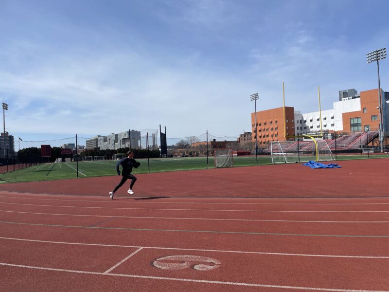 Girl sprinting along a red track.