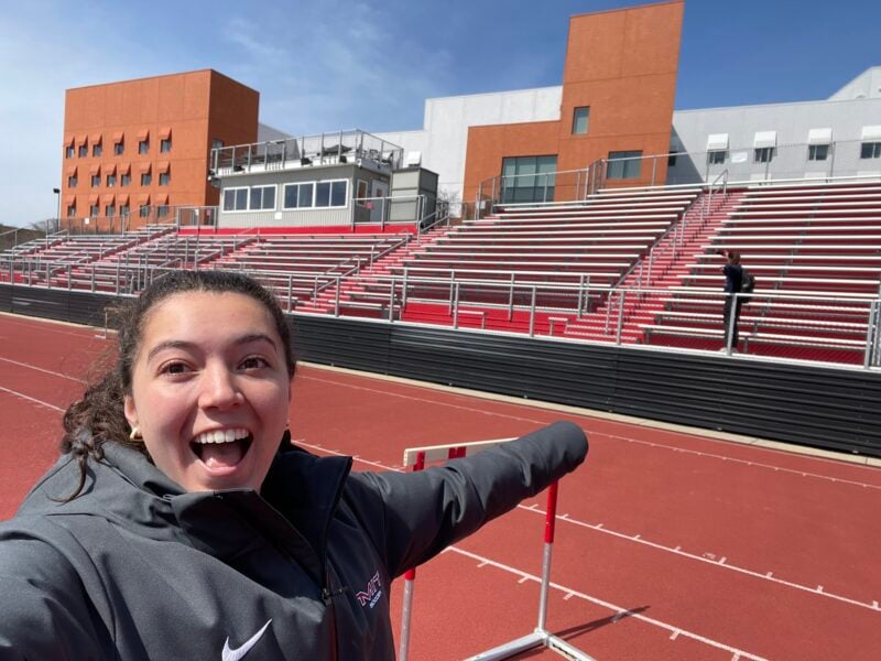 Selfie with a girl pointing at another person taking a selfie on the bleachers.