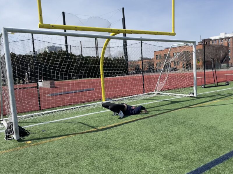 Girl falling after a handstand in front of a soccer goal