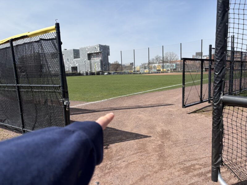 Girl pointing at entrance to baseball field.