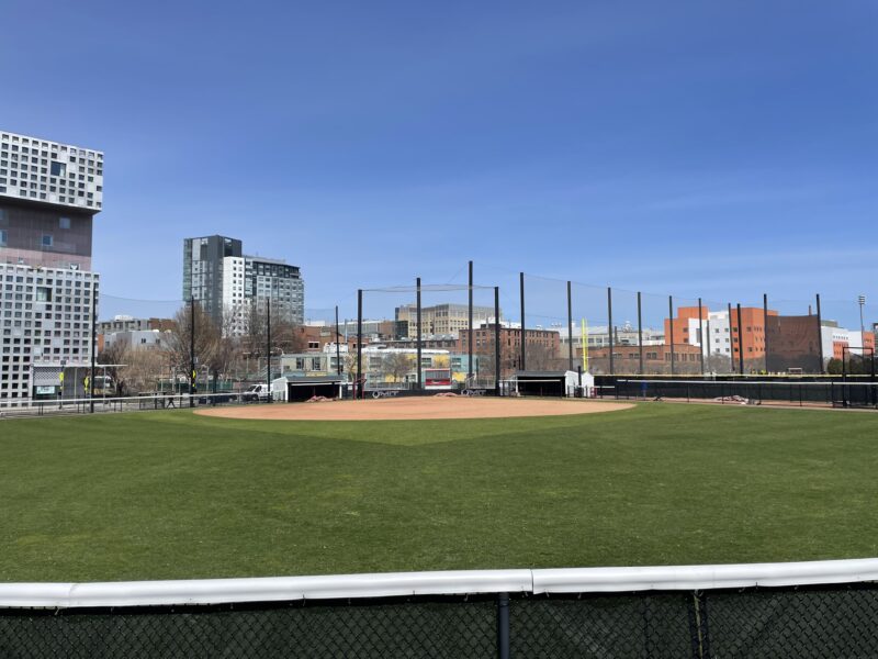 Softball field with buildings in background.