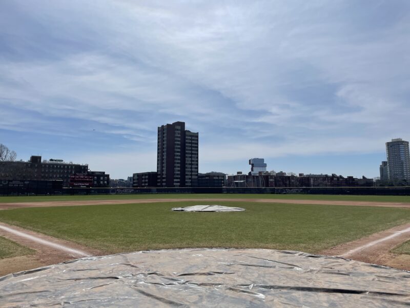 Baseball field view from home plate with buildings in background.