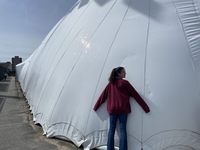 Girl hugging ginormous white tennis court bubble