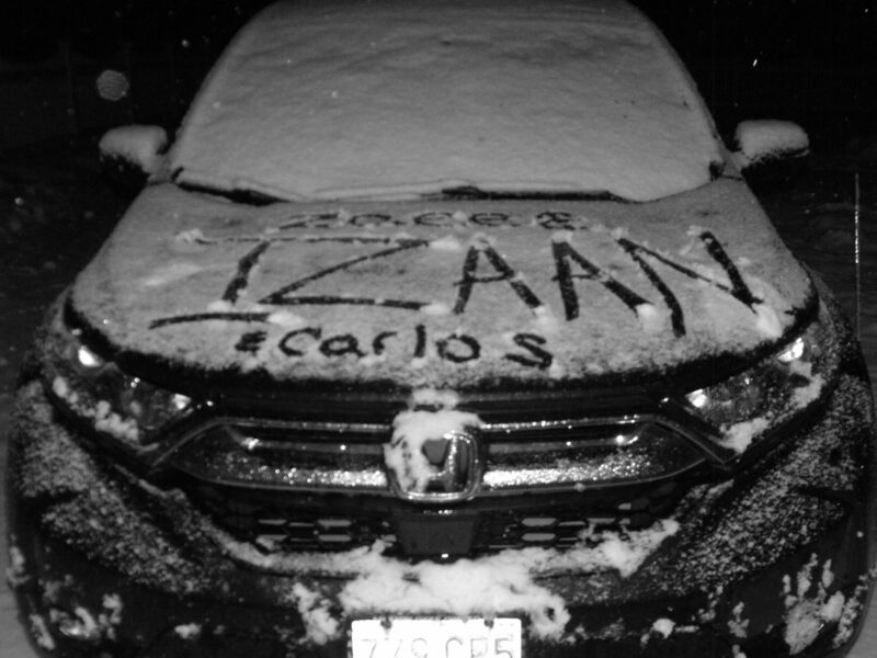 A black and white image of a car covered in snow.