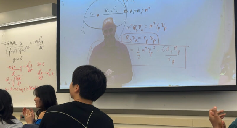 Photo of peter Dourmashkin on a projector screen in a classroom.