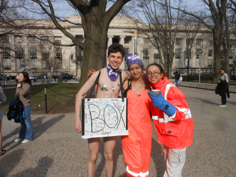 A boy in a purple bandanna wearing a box that says