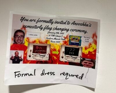 A single sheet of printer paper, slightly wrinkled and taped to a white wall, advertises “Anooshka’s semesterly flag-changing ceremony.” The text is in a dramatic cursive font above a collage set against cartoonish flames: photos of a bespectacled man saying “i miss yulia,” Guy Fieri giving double thumbs-up, a Spongebob image with the speech bubble “Be there or be squar,” and two small photos of the same rectangular flag display—one labeled “FLAVORTOWN,” the other covered by black boxes with white question marks, linked by a green arrow. Event details read “January 29th 2025, 10 PM (sharp!), Fariborz Maseeh Hall, Room 3009.” A handwritten note along the bottom declares “Formal dress required!”
