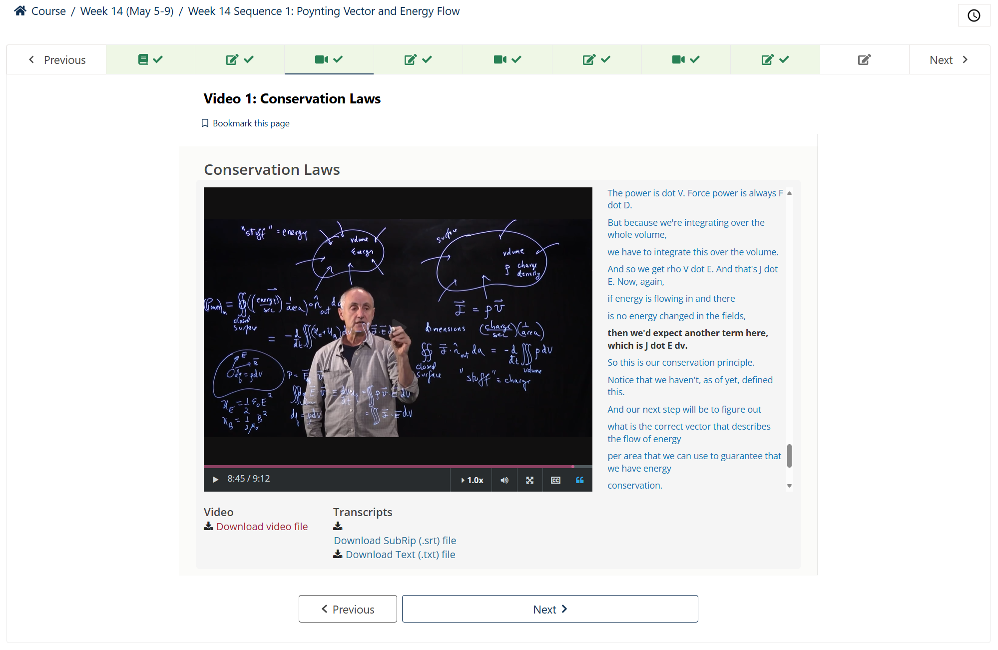 Photo of professor behind a glass board using neon markers to explain conservation laws.