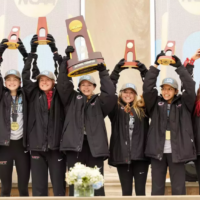 Runners holding big trophies over their head on a podium.