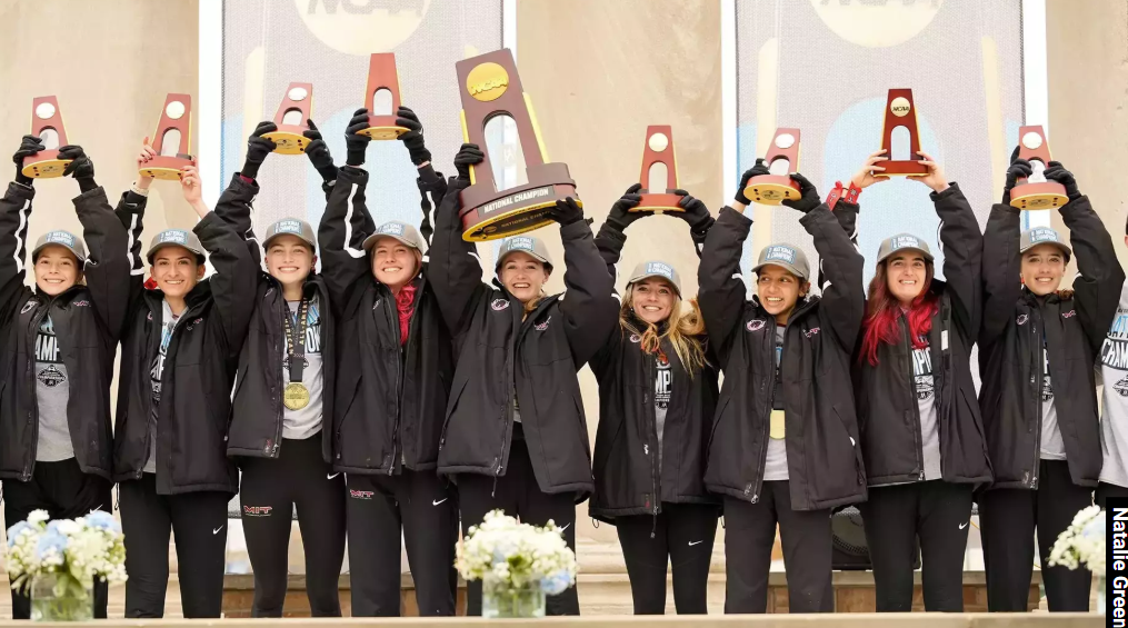 Runners holding big trophies over their head on a podium.