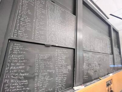 A set of nine blackboards almost completely covered in names of famous women