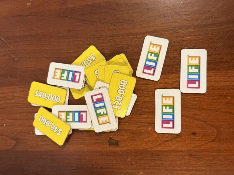 life tiles scattered on a table, with money values on one side and the word