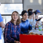 Students sitting in front of a table eating and drinking water.