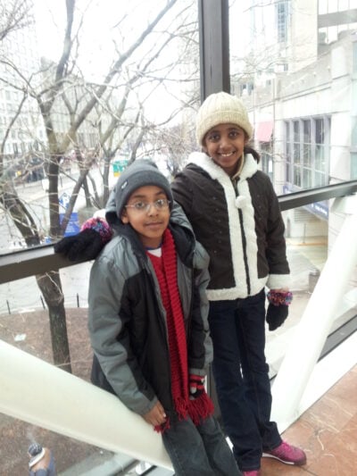 Nine-year-old me and eleven-year-old Raiye standing on a Boston skybridge wearing heavy winter clothing.