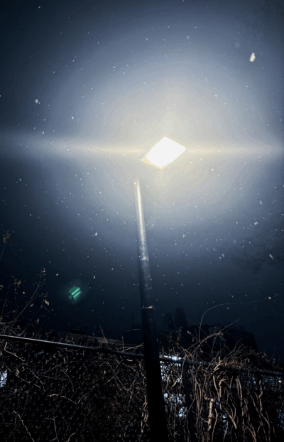 bright streetlight at midnight illuminating snow particles