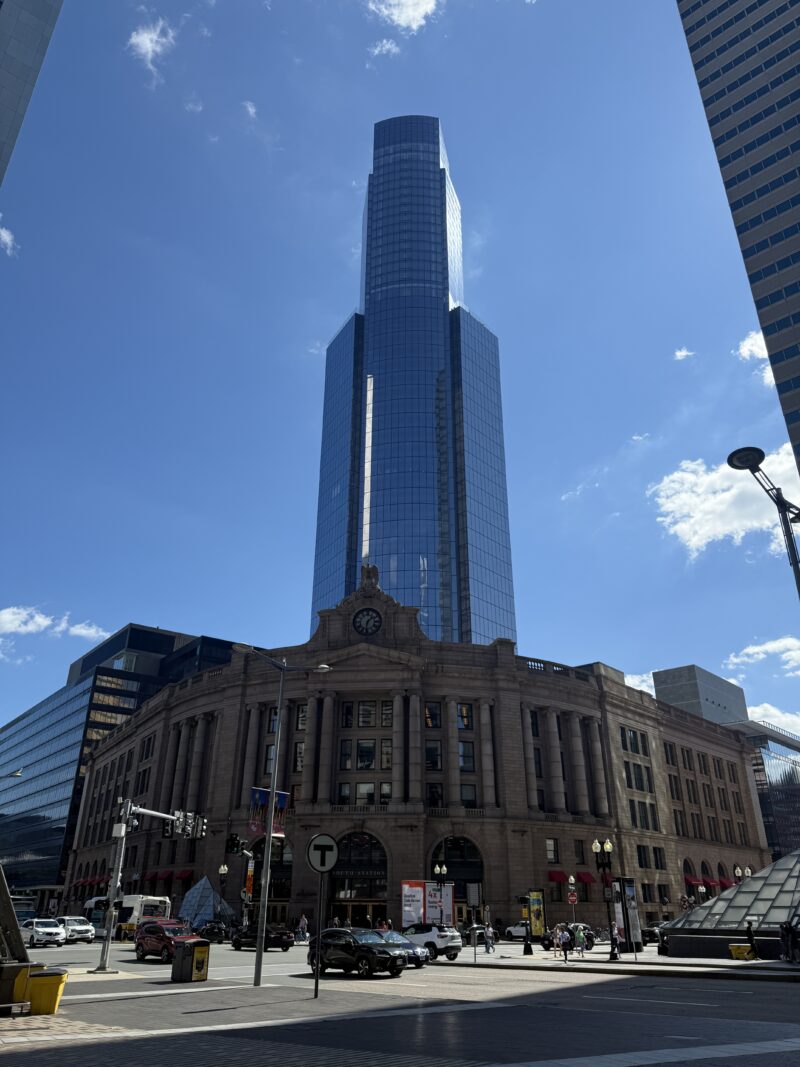 a skyscraper towering behind a train station