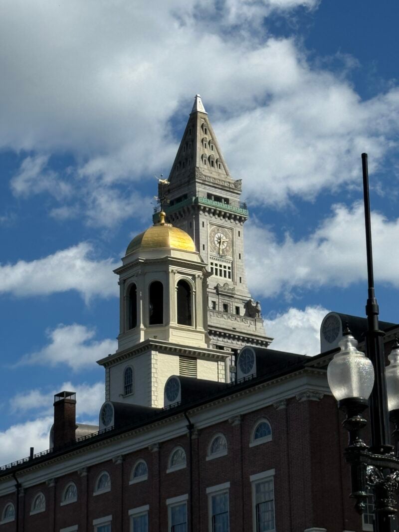 a brick building with a gold dome in the foreground and a tower in the background