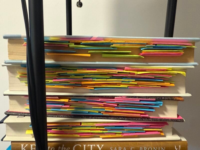 books stacked on top of each other with lots of sticky note annotations sticking out