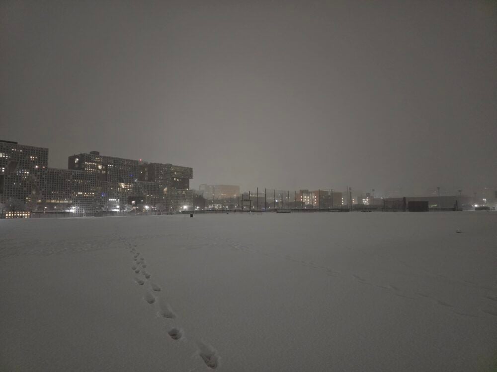 snow covering a field in front of a dorm building